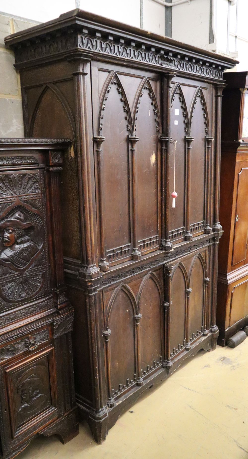 A 19th century French Gothic design stained pine press cupboard with two doors enclosing two shelves and three short drawers over two f